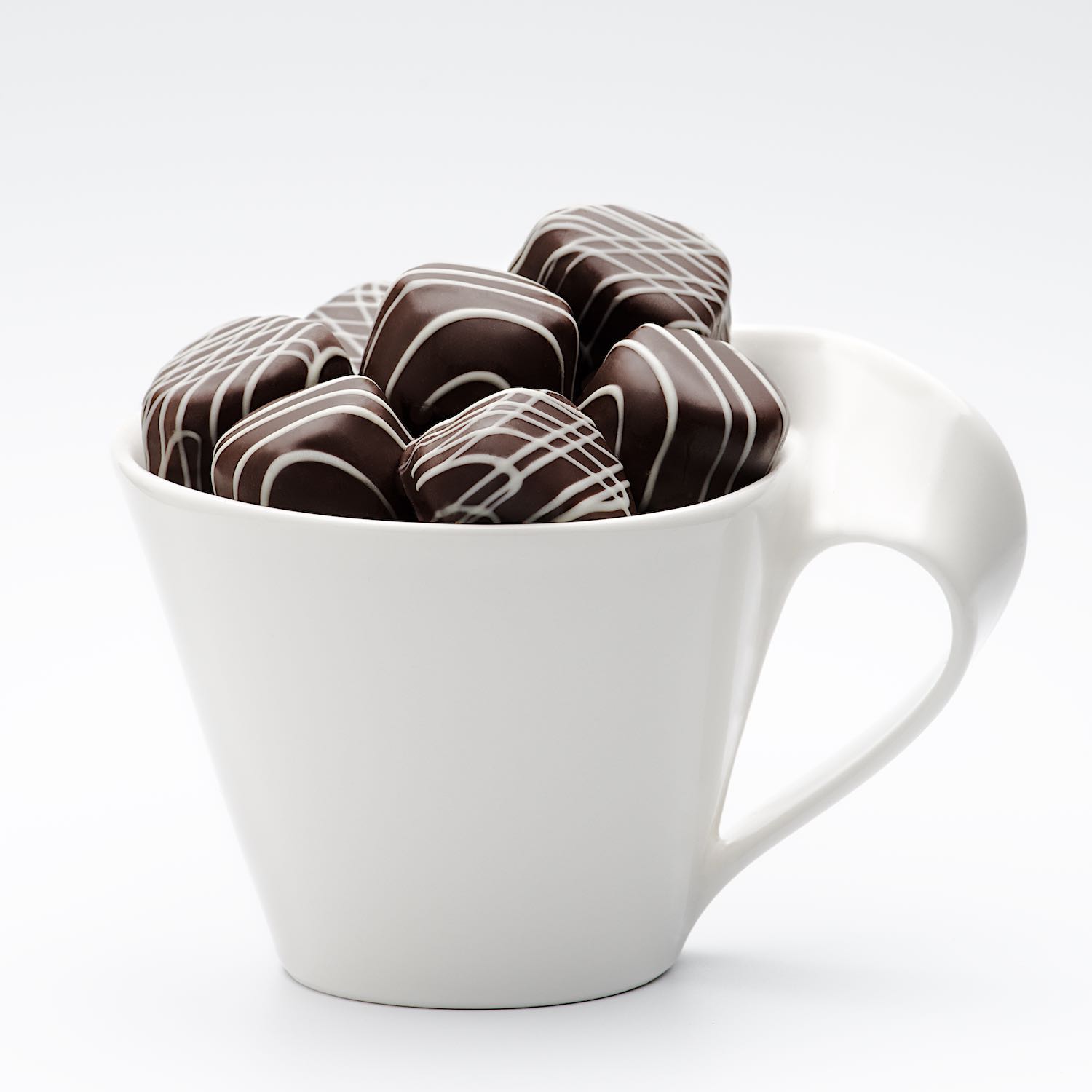 Dark chocolate candy in white coffee cup on white background © Bret Doss Commercial Food & Product Photography  Seattle